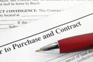 A close-up view of a real estate purchase contract with a red pen indicating the importance of reviewing and signing the document.