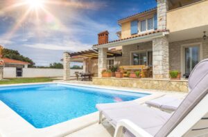 Sunny day at a luxurious private villa with a swimming pool, comfortable loungers, and a welcoming outdoor patio, perfect for those buying a property under the attorney-guided golden visa practice areas.